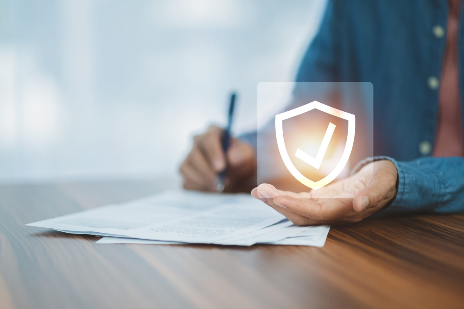 Person signing a document with a shield icon symbolizing security.