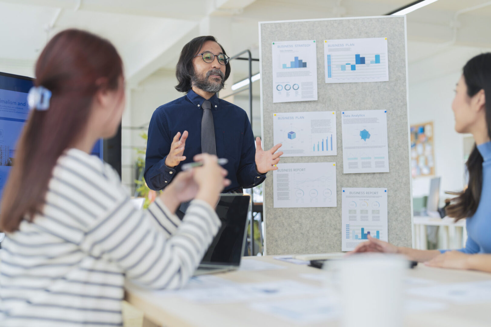 Man presenting data charts to colleagues in a meeting.
