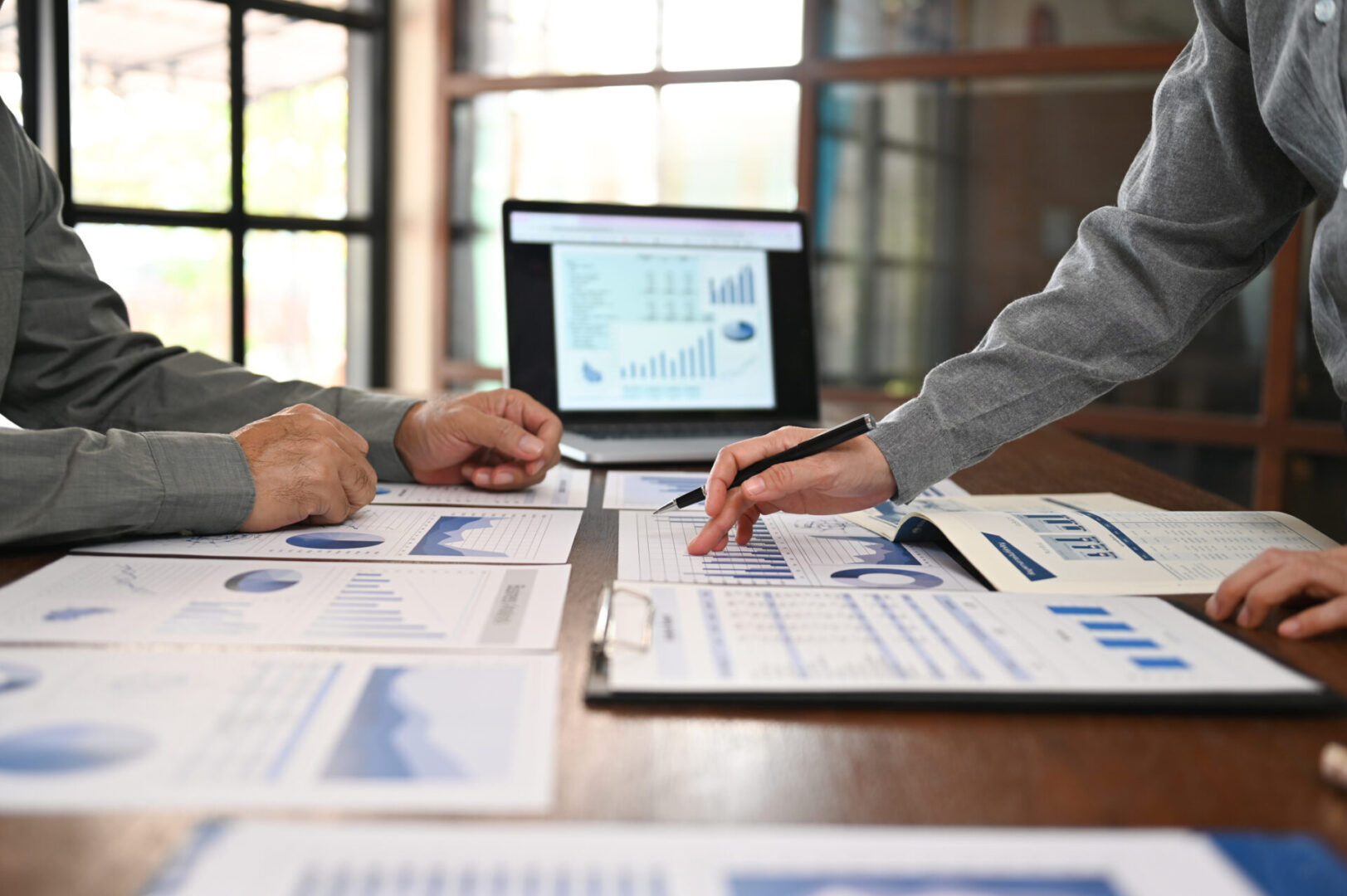 Two people analyzing financial charts and data at a desk.
