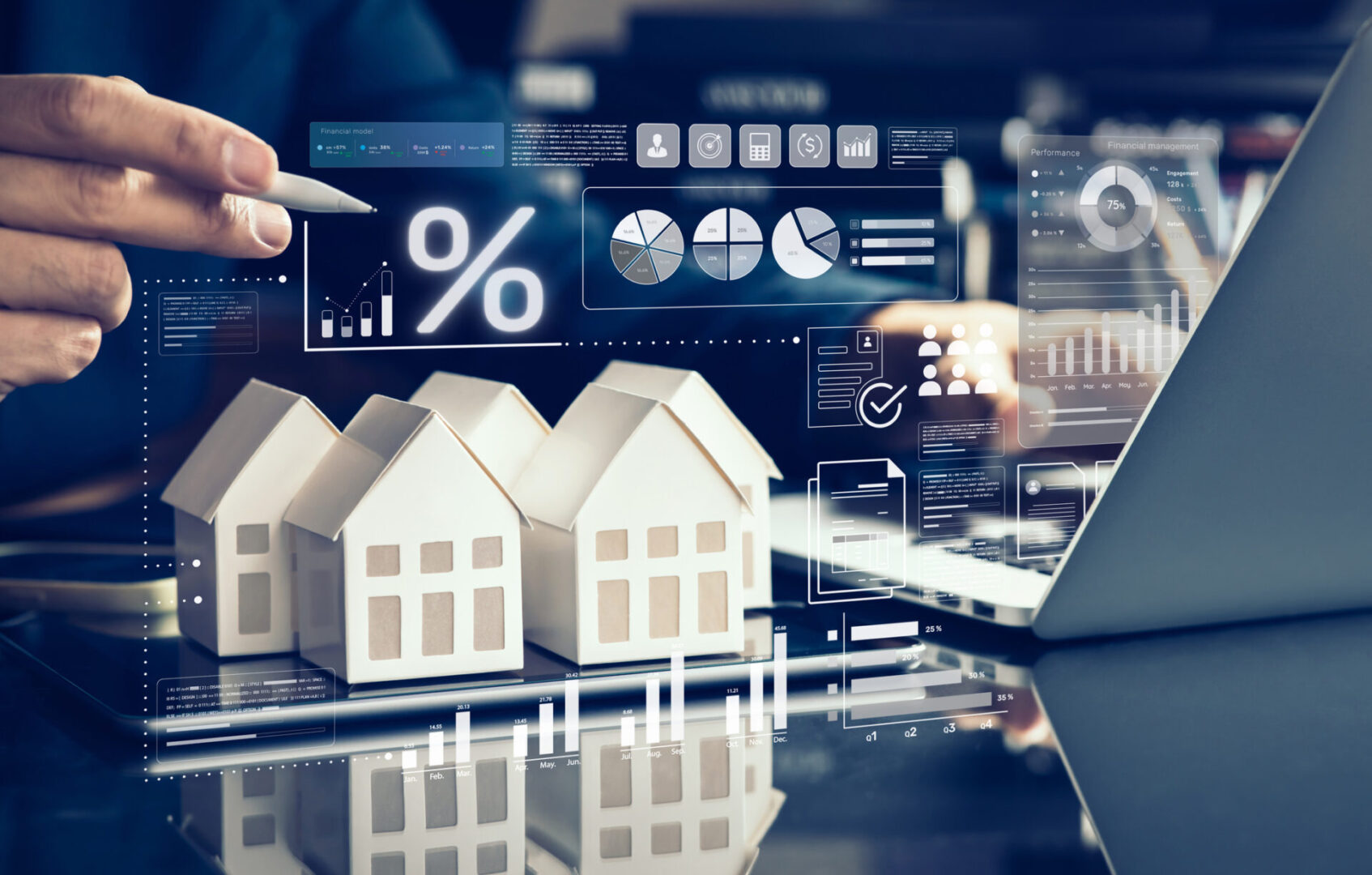 Miniature houses with financial graphs and a calculator in the background.
