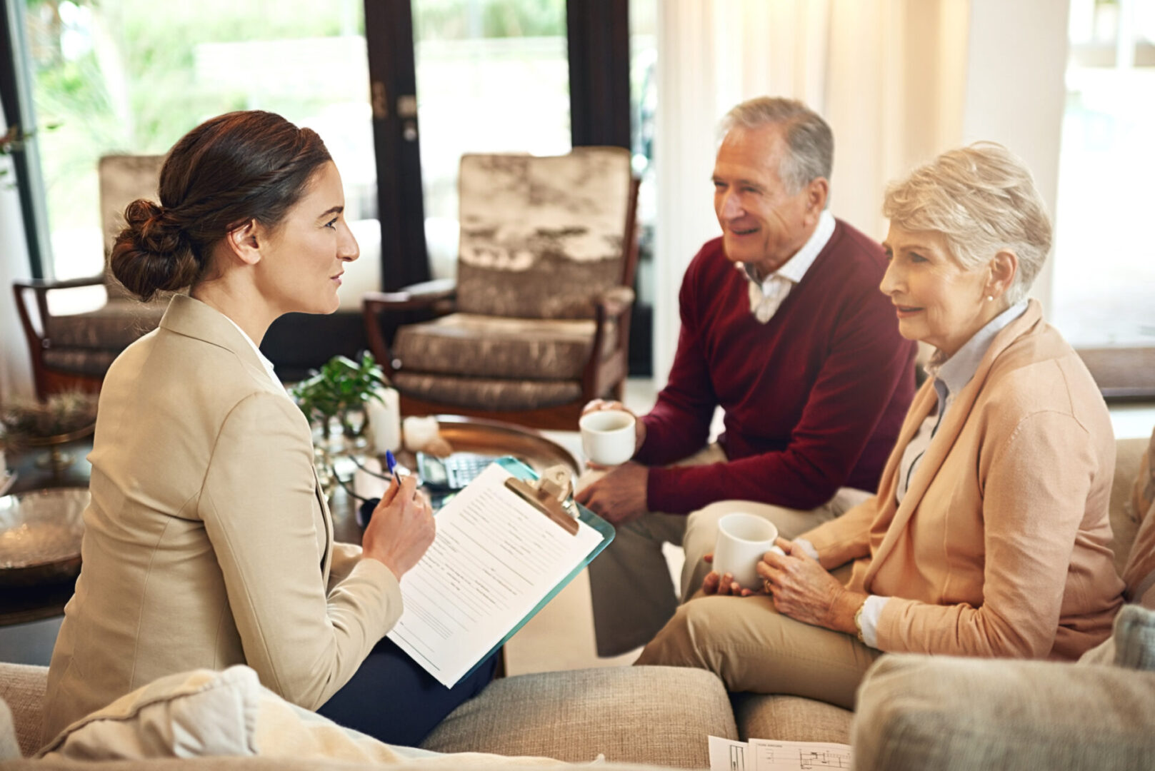 A professional woman consulting an elderly couple in a cozy living room.