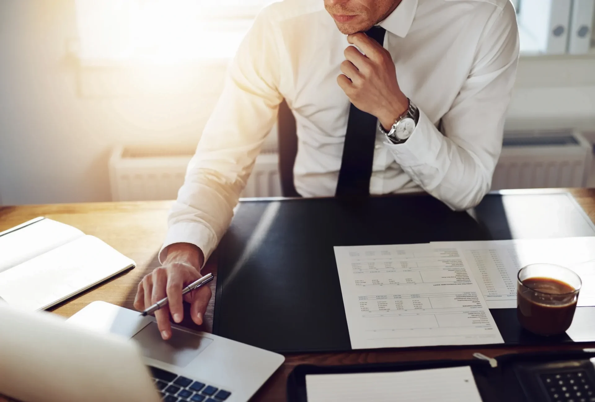 Businessman working with documents and smartphone at desk.