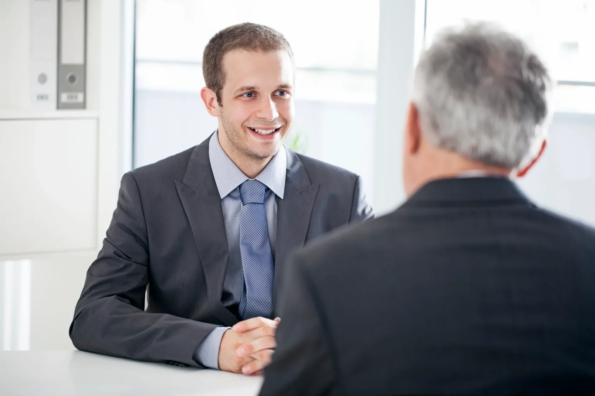 Two men in a business meeting, one smiling.