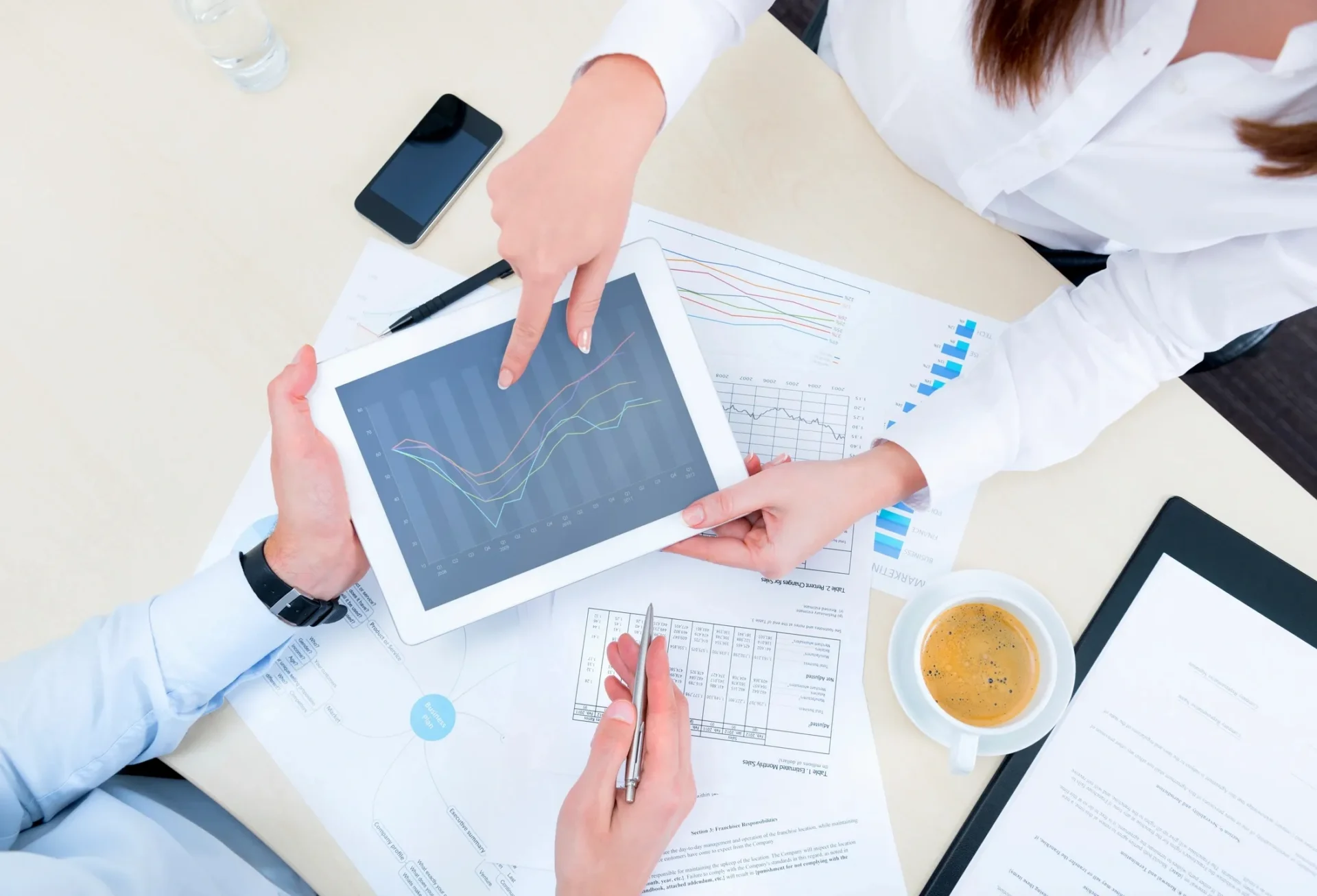 Two professionals discussing data displayed on a tablet during a meeting.
