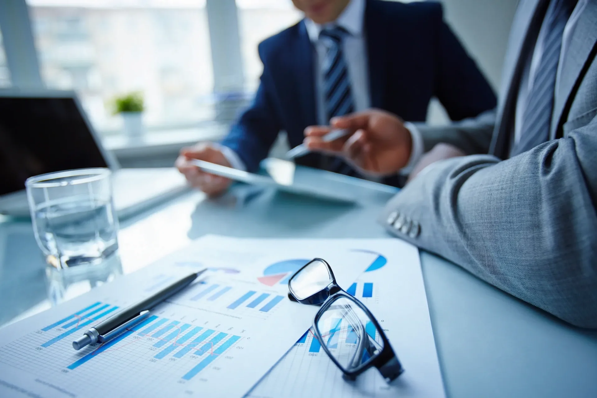 Business meeting with charts and glasses on table.