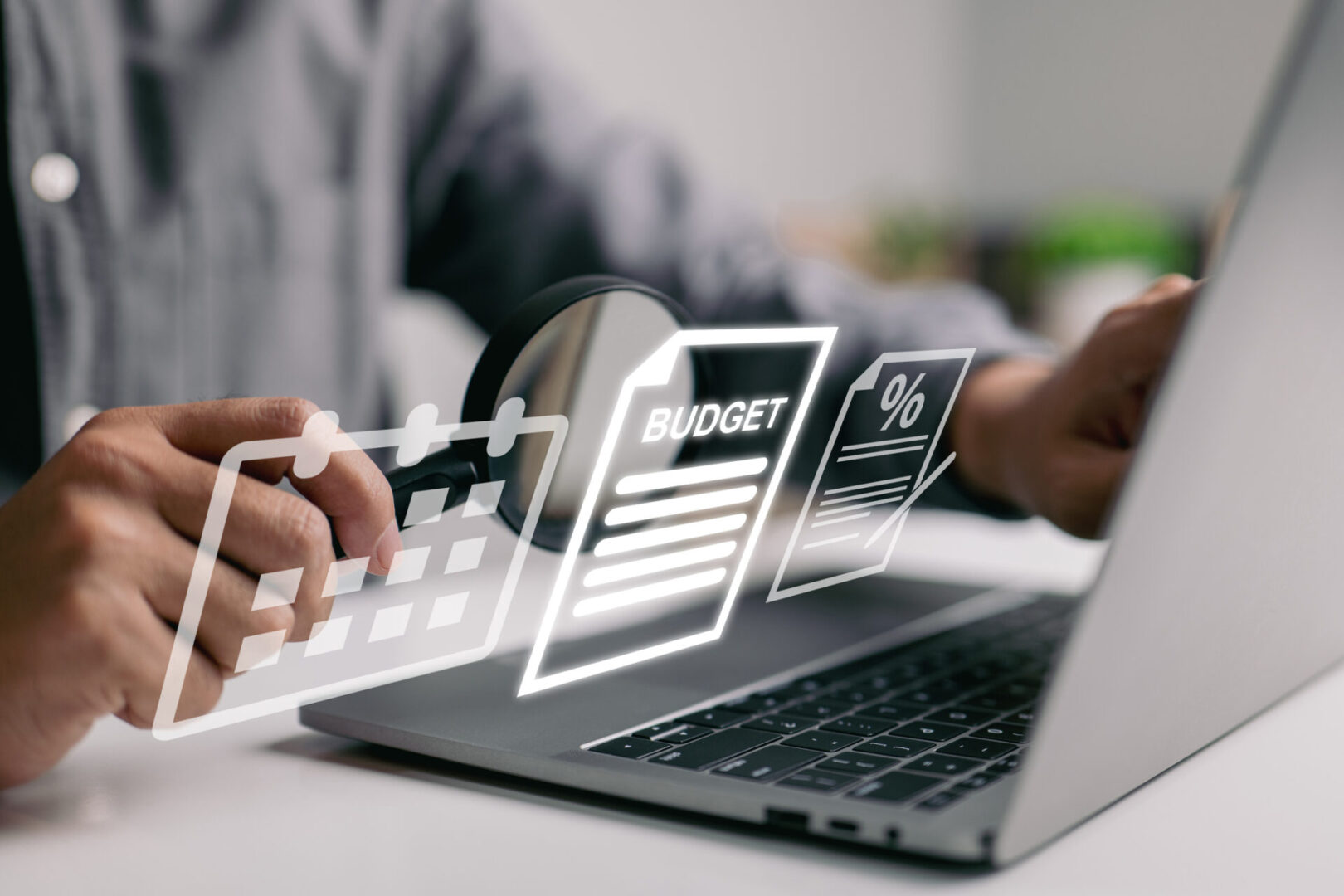 Person working on budget planning using a laptop with digital financial graphics.