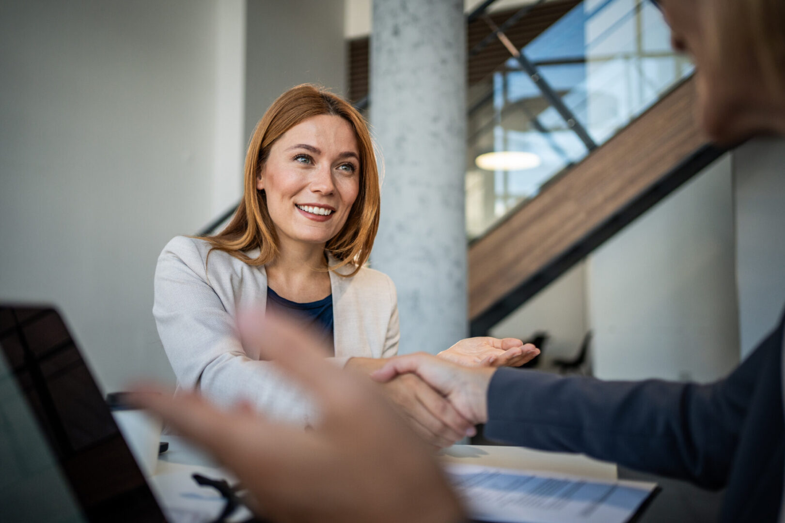 A woman smiling warmly during a conversation in a modern office.