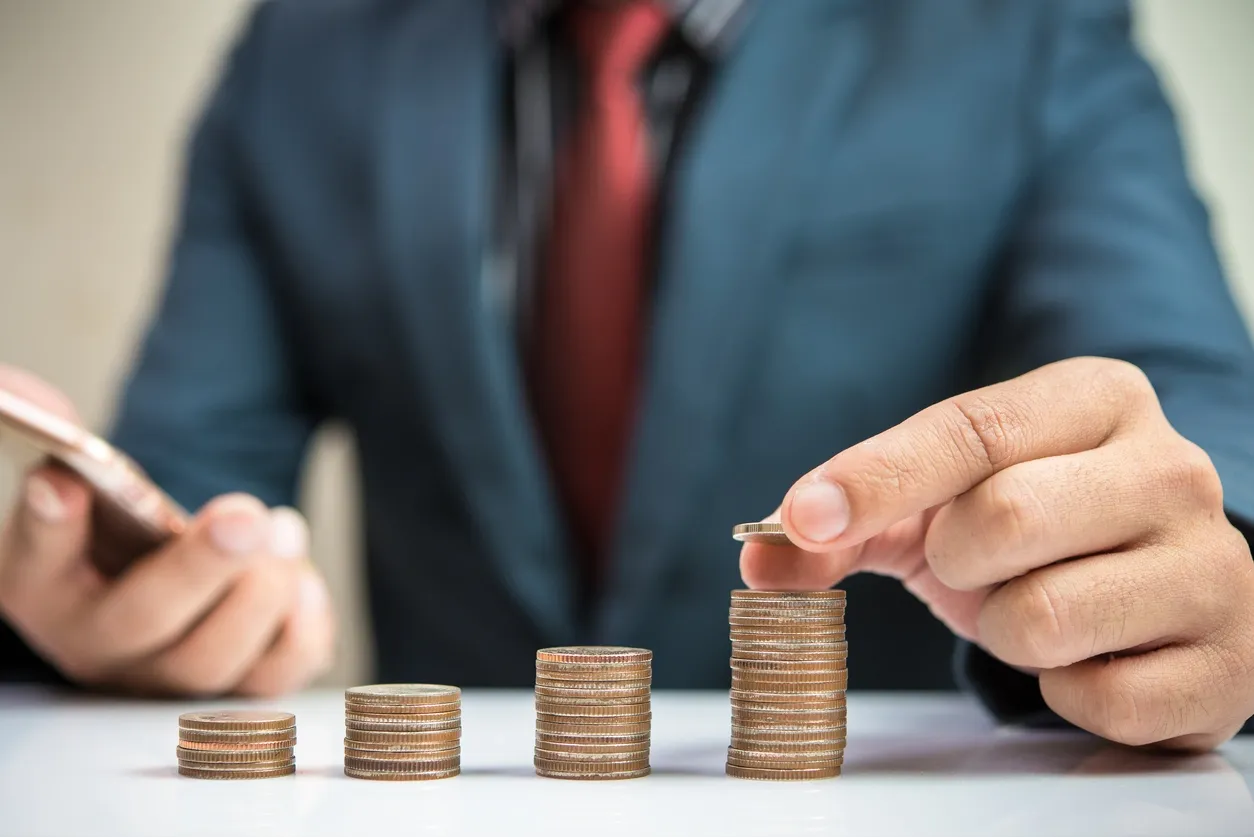 Hand stacking coins symbolizing financial growth.