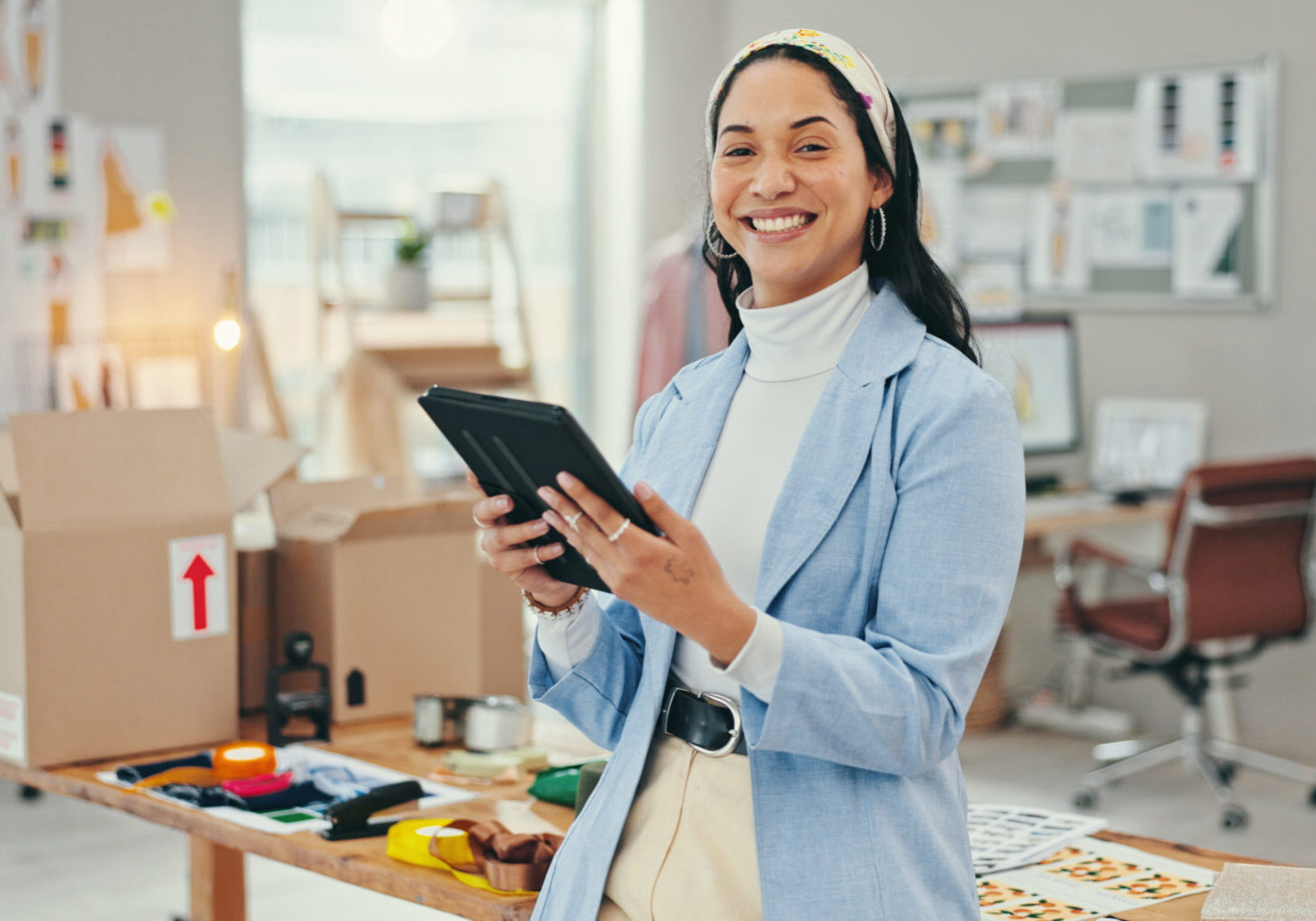 Smiling woman using a tablet in a creative workspace.